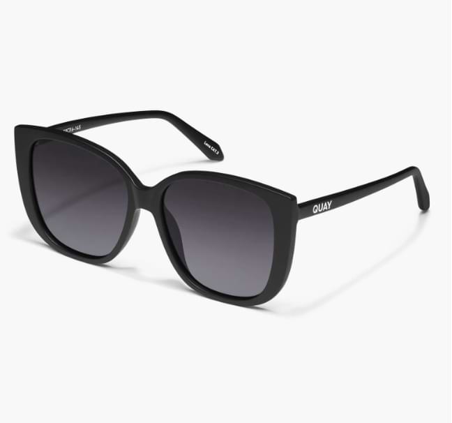 Angled view of Quay Ever After sunglasses with black cat eye frames and gradient gray lenses.